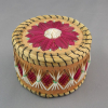 A photograph of the quillbox showing the lid and body. There is a fuchsia and white floral design on the lid, and fuchsia and white geometric patterns on the body.